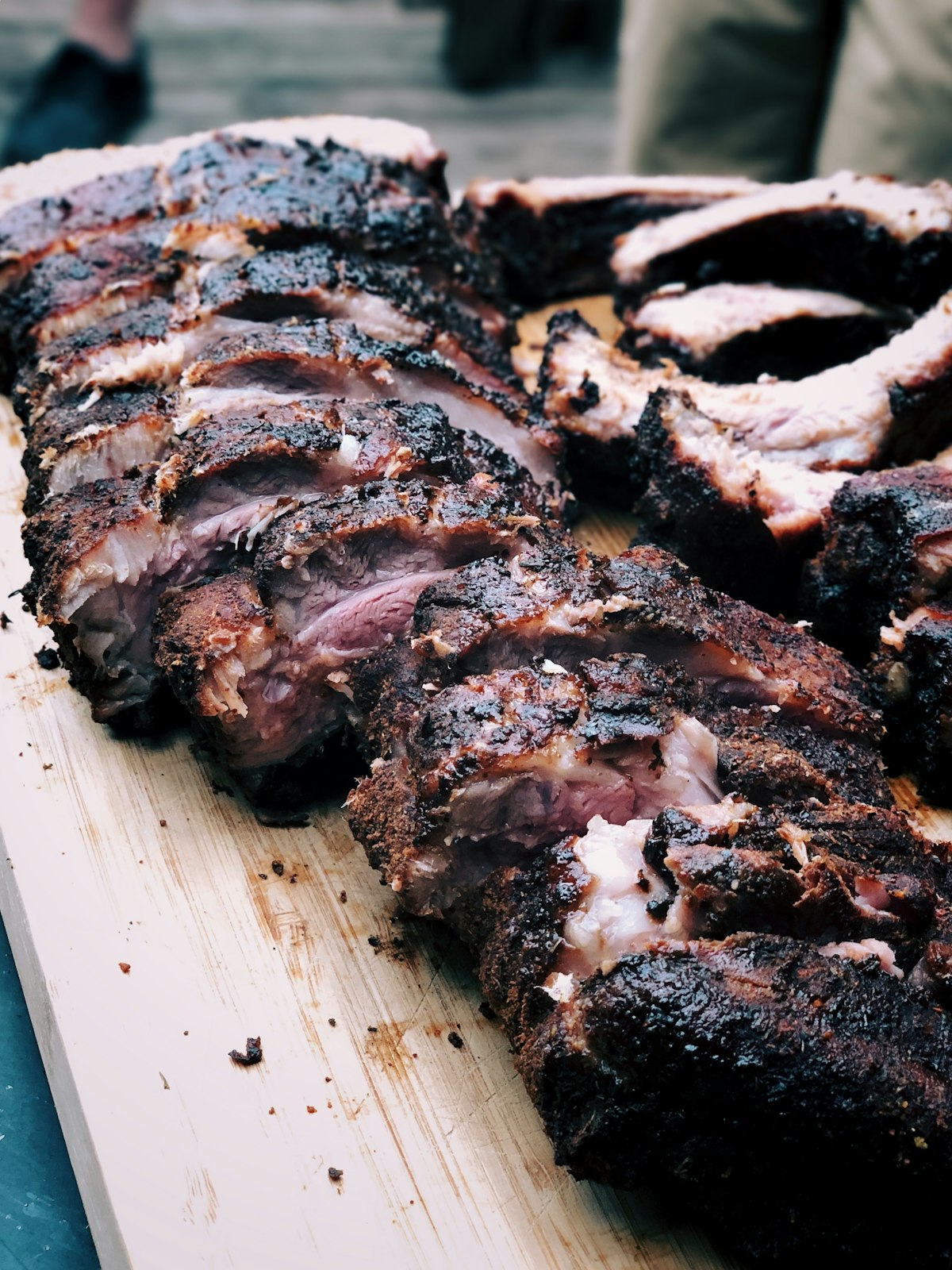 Sliced smoked ribs with a dark bark and visible smoke ring on a wood cutting board