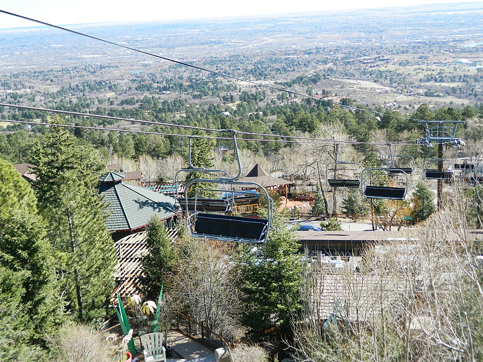 Chairlift climbing over Cheyenne Mountain Zoo, with Colorado Springs in the valley below.